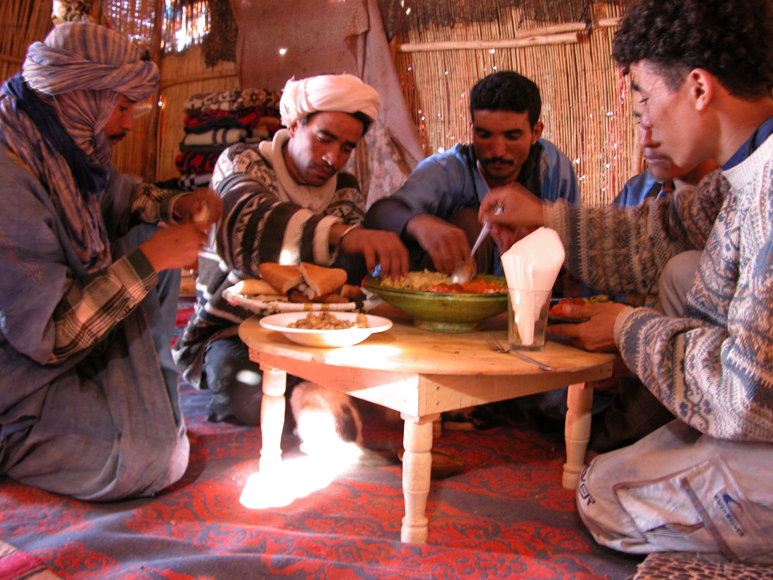 Grupo compartiendo una comida con guías locales durante un viaje por Marruecos